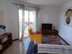 a living room with a couch and a tv at Appartement NANA A 34 - Appartement Cosy et Lumineux - Vue Panoramique- Centre ville- - Cuisine équipée- CLIM- WIFI - NETFLIX-Parking Public Gratuit-Garage privé payant in Cayenne