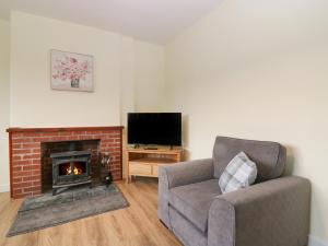 uma sala de estar com uma lareira, uma cadeira e uma televisão em Bankhead of Lour Bungalow em Forfar