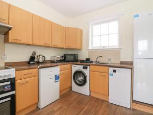 a kitchen with wooden cabinets and a washer and dryer at Bankhead of Lour Bungalow in Forfar