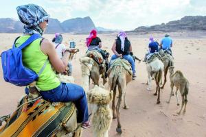 a group of people riding camels in the desert at Joker camp Wadi Rum in Disah