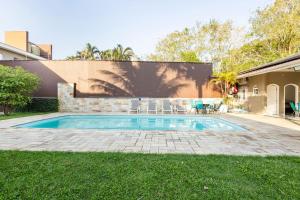 a swimming pool in a yard next to a house at Casa Alto Padrão Piscina Aquecida e Sauna in Bertioga