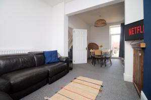 ein Wohnzimmer mit einer schwarzen Ledercouch und einem Tisch in der Unterkunft Central Cardiff - 3 Bedroom Home - Walk to Shopping Town Centre And Cardiff Castle in Cardiff