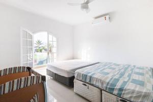 a white bedroom with a bed and a window at Casa Alto Padrão Piscina Aquecida e Sauna in Bertioga +28 photos
