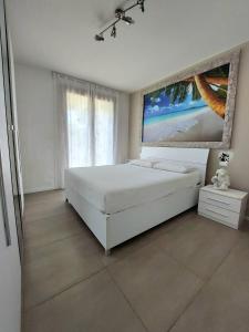 a bedroom with a white bed and a painting on the wall at Residence Jesolo Lido centro con piscina in Lido di Jesolo