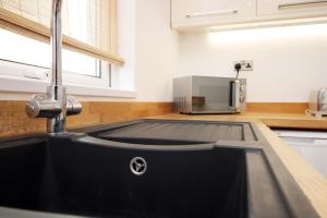 eine Küche mit einer schwarzen Spüle und einer Mikrowelle in der Unterkunft Central Cardiff - 3 Bedroom Home - Walk to Shopping Town Centre And Cardiff Castle in Cardiff + 75 Fotos