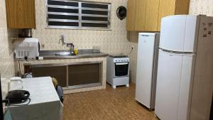 a kitchen with a white refrigerator and a sink at Casa muito espaçosa privativa com Piscina, Churrasqueira e área gourmet in Araruama