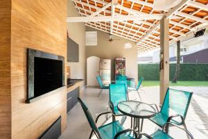 a patio with blue chairs and a flat screen tv at Casa Alto Padrão Piscina Aquecida e Sauna in Bertioga