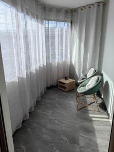 Cette chambre dispose d'une chaise et d'une fenêtre avec des rideaux. dans l'établissement Paris La Defense - Courbevoie vue sur Seine, à Courbevoie