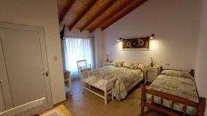 a bedroom with two beds and a table and a window at ANIDO Cabañas y Monoambientes in Lago Puelo