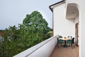 a balcony with a table and chairs and a tree at B&B Moderno in Fažana