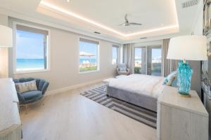 a bedroom with a bed and a chair and windows at Beach Front Residence 107 located at The Ritz-Carlton in Upper Land