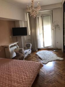 a bedroom with a bed and a television and a chandelier at Milošević in Šabac