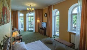 1 dormitorio con 1 cama, TV y ventanas en Premier Hotel Palazzo, en Poltava