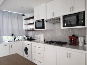 a kitchen with white cabinets and a stove and microwave at La Casita Azul in Castries