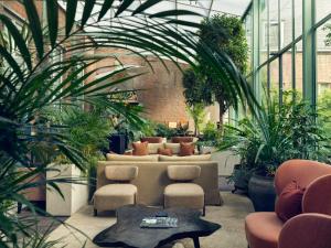 un salón acristalado con plantas, mesa y sillas en Botanic Sanctuary Antwerp - The Leading Hotels of the World, en Amberes