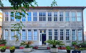 un edificio con grandes ventanas y plantas delante de él en LA CASA ALTA en la ruta del Camino de Santiago, en A Guarda