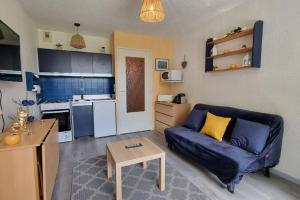 a living room with a blue couch and a kitchen at Chez K&D Au Col De l'Arzelier in Château-Bernard