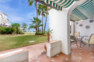 a patio with a table and chairs and palm trees at Playa Lucera in Sitio de Calahonda