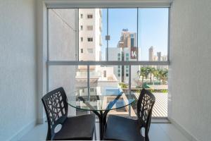 a glass table and chairs in a room with a window at Edifício Metropolitan Barcelona - Jardim Goias - MBC in Goiânia