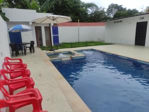 a swimming pool with a red chair and an umbrella at Casa Quinta el Refugio in Flandes