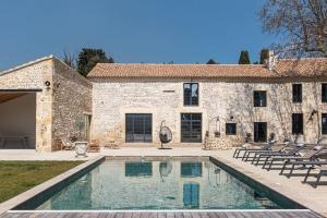 uma piscina em frente a uma casa de pedra em Mas Mandine, en Provence em Arles