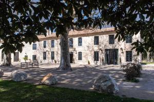 um grande edifício de pedra com uma árvore em frente em Mas Mandine, en Provence em Arles