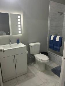 a white bathroom with a toilet and a sink at Oak Villa MontegoBay2 Queen Room in Montego Bay