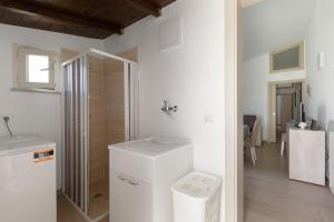 baño con ducha y nevera blanca. en Home in Salento Sole by BarbarHouse, en Carpignano Salentino