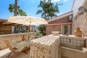 une terrasse avec une table et un parasol dans l'établissement Home in Salento Sole by BarbarHouse, à Carpignano Salentino