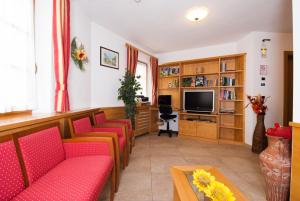 a waiting room with red chairs and a tv at Garni Manuela in Cavalese