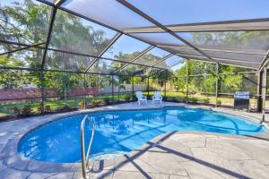 an indoor swimming pool with a large glass house with a patio at Lazy Manatee Pool Home in Bradenton