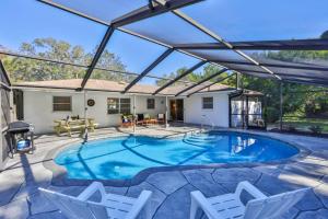 a swimming pool with a pergola and chairs at Lazy Manatee Pool Home in Bradenton