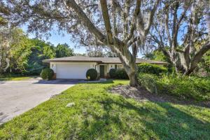 a house with a tree in front of a driveway at Lazy Manatee Pool Home in Bradenton