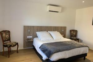 a bedroom with a large bed and two chairs at Appartement RDC in Remoncourt