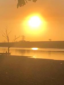 une personne assise sur un banc à côté d'un lac au coucher du soleil dans l'établissement Rancho próximo rio pesca Sales, à Sales