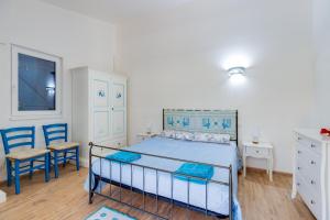 a bedroom with a bed and two blue chairs at Villetta Lucia a due passi dal mare in Putzu Idu