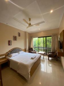 a bedroom with a large bed and a large window at Jewel Resort in Lonavala