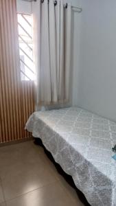 a bedroom with a bed and a window with curtains at kitnet completa no Centro in Carolina