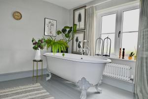 baño con bañera blanca y ventana en Leo's Holiday Cottage en Doddington