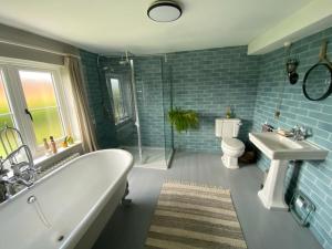 ein Badezimmer mit einer Badewanne, einem Waschbecken und einem WC in der Unterkunft Leo's Holiday Cottage in Doddington
