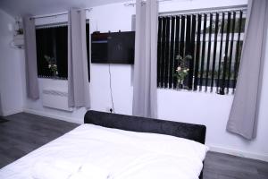 uma cama num quarto com duas janelas e uma televisão em The Lodge Oldham em Oldham