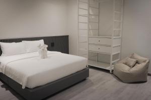 ein Schlafzimmer mit einem weißen Bett und einem Stuhl in der Unterkunft arche second floor in Ban Riang