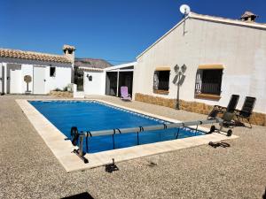 uma piscina com duas cadeiras e uma casa em Casita Estherose em Vélez Rubio