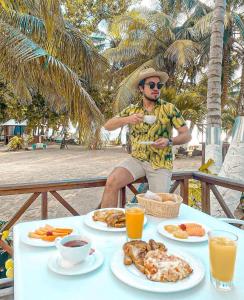 un hombre sentado en una mesa con platos de comida en Hotel Reina del Mar By Dorado en San Andrés