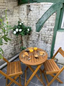 een houten tafel en stoelen met eten erop bij Cottage Relax. in Rouen