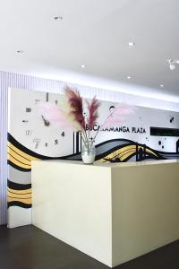 a wall with a clock and a vase with flowers at Hotel Bucaramanga Plaza in Bucaramanga