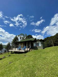 una casa en una colina con un patio verde en Cabana Monte - Pousada Colina dos Ventos, en Urubici