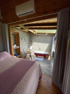 1 dormitorio con 1 cama y bañera en una habitación en Cabana Monte - Pousada Colina dos Ventos, en Urubici
