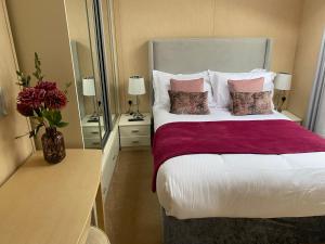 ein Schlafzimmer mit einem großen Bett und einem Spiegel in der Unterkunft Hot Tub Lodge with Panoramic Views & Free Golf in Swarland