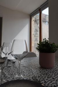 een tafel met twee wijnglazen op een tafel met een plant bij * La Tour : Vue imprenable sur la ville * in Luxeuil-les-Bains